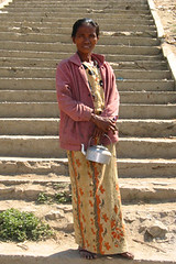 vrouw met een keteltje onder aan trap Mandalay Birma